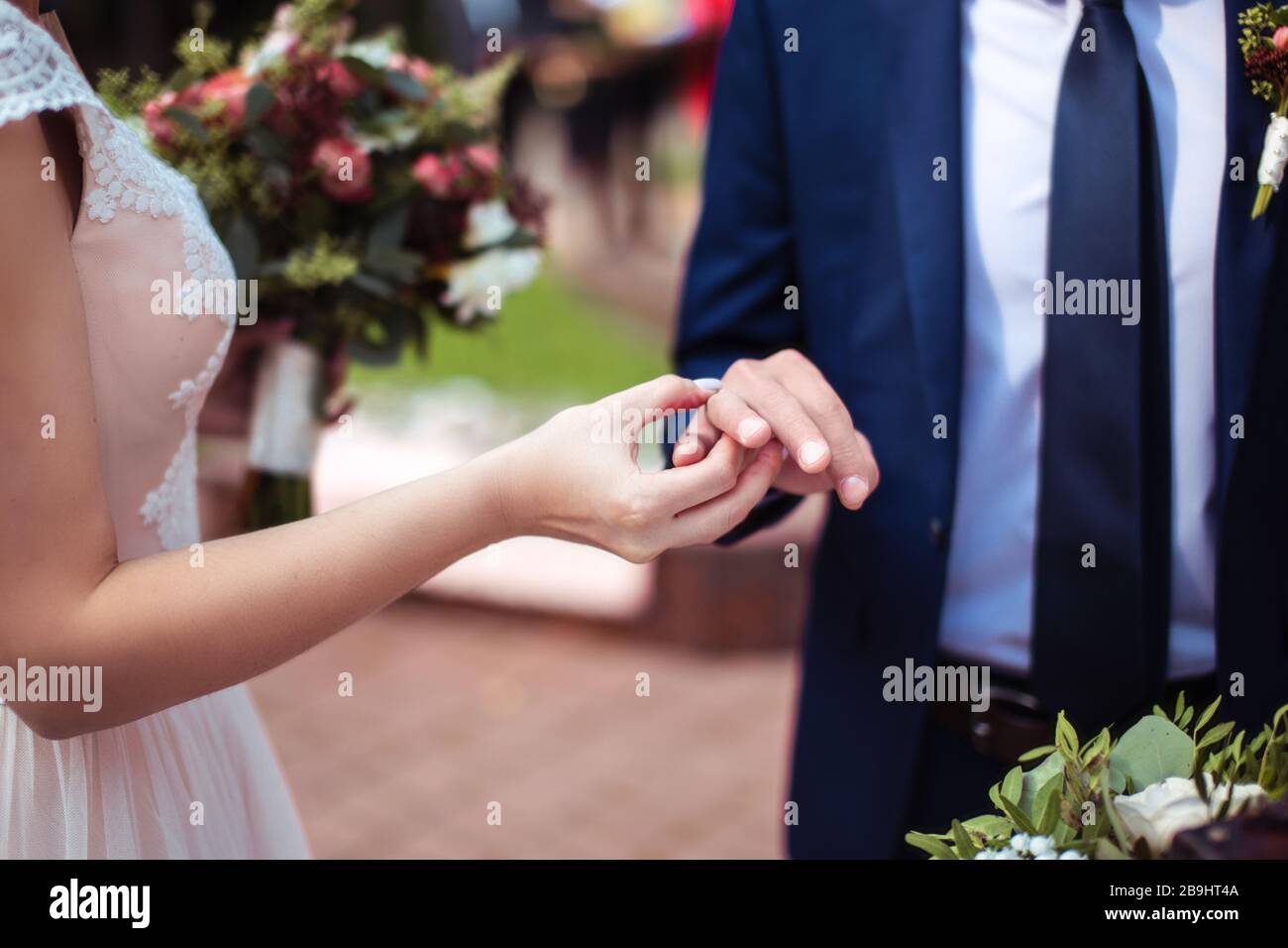 Mariée mettant l'anneau de mariage doré sur le doigt de groom. Cérémonie de mariage Banque D'Images