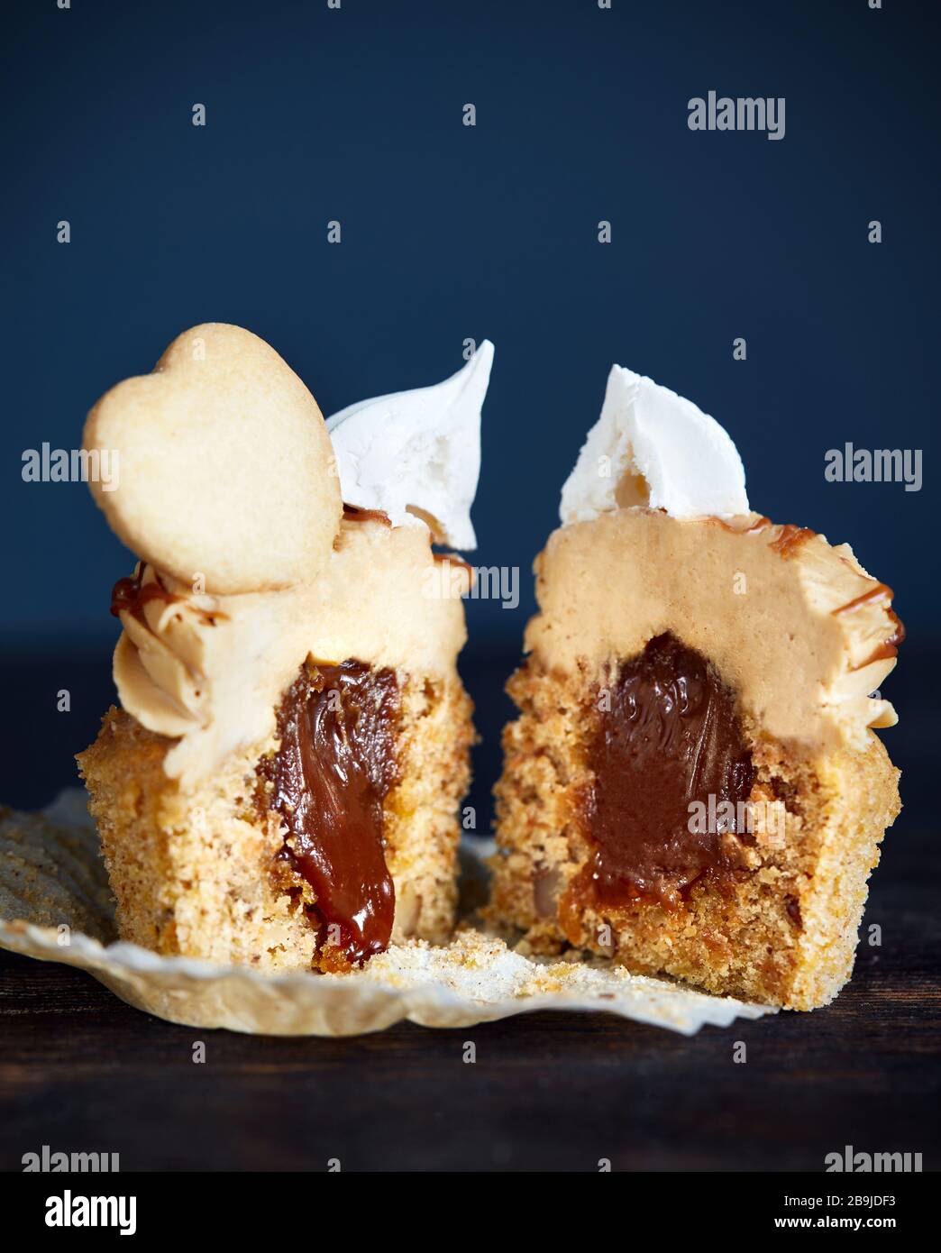 Coupe de cupcake de Carrot au caramel, noix et épices décorées de biscuit en forme de coeur, meringue et caramel salé sur fond sombre gros plan Banque D'Images
