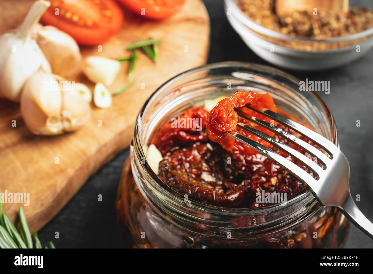 Faire cuire des tomates séchées dans un pot en verre avec de l'huile d'olive, de l'ail et des épices, gros plan. Banque D'Images