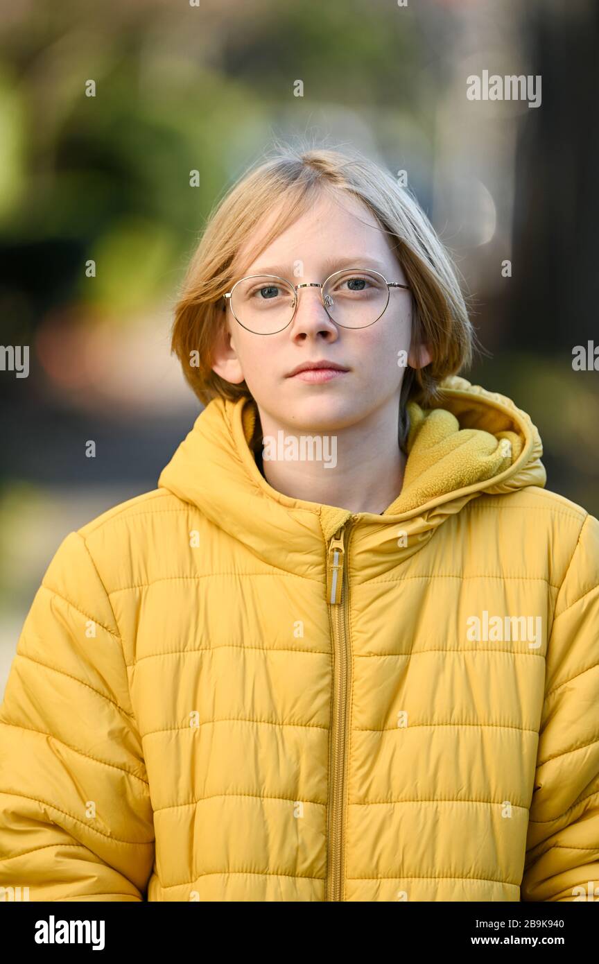 Tween garçon avec des lunettes et une veste jaune souriant regardant l'appareil photo Banque D'Images