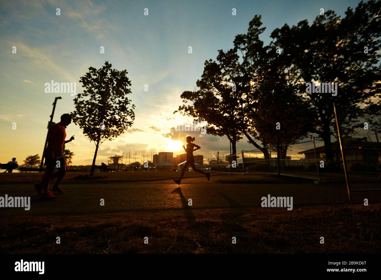 Silhouette d'une femme qui coute au coucher du soleil à Boston. Banque D'Images
