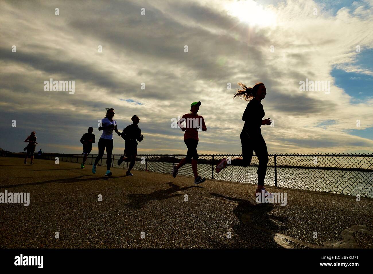 Un groupe de coureurs silhouettés près du port de Boston. Banque D'Images