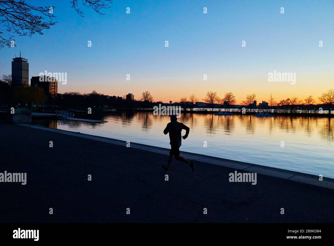 Un homme sur une course au coucher du soleil le long de la rivière Charles à Boston. Banque D'Images