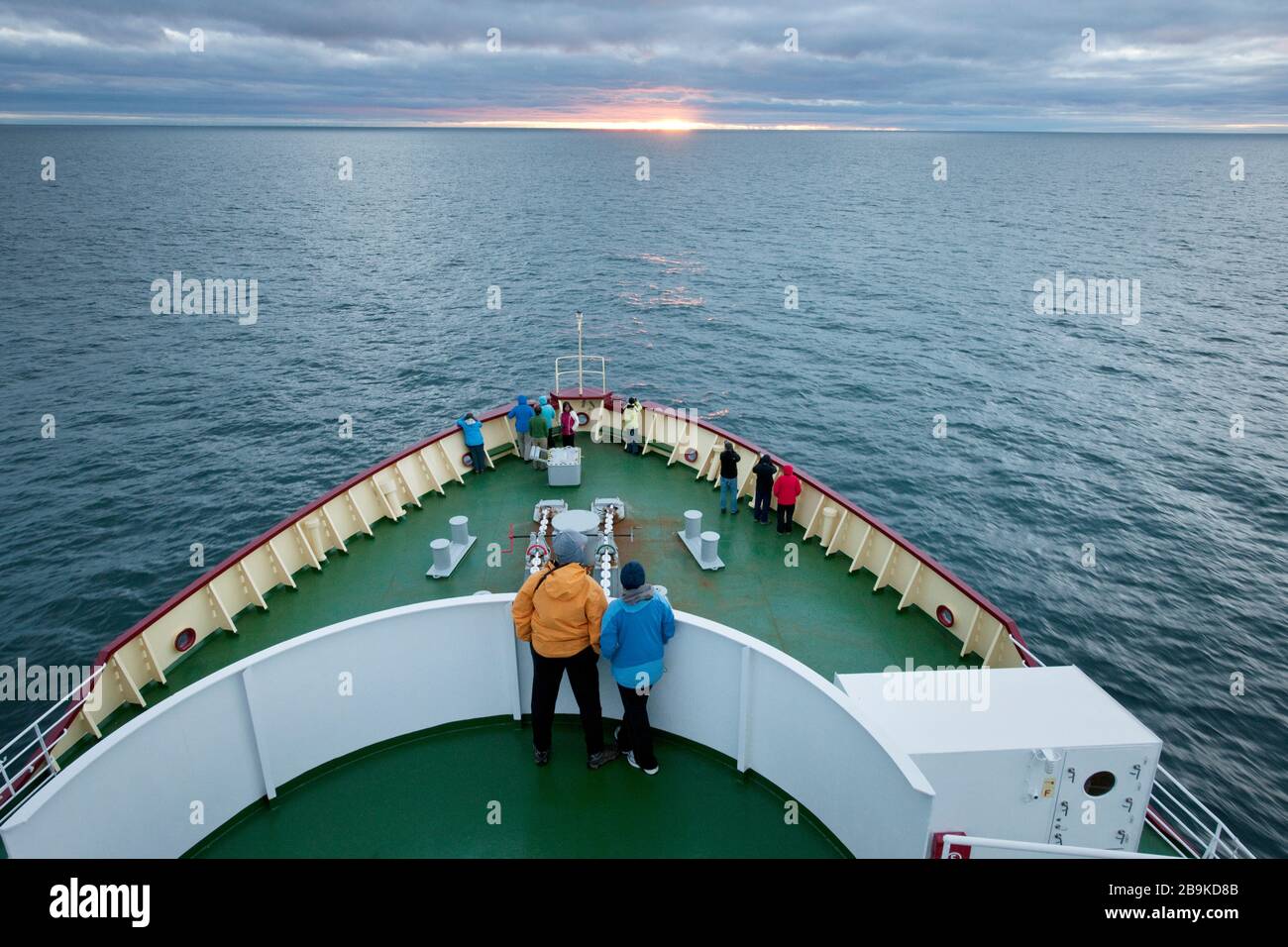 Touristes se tenant sur le pont d'un bateau et en admirant le lever du soleil. Banque D'Images