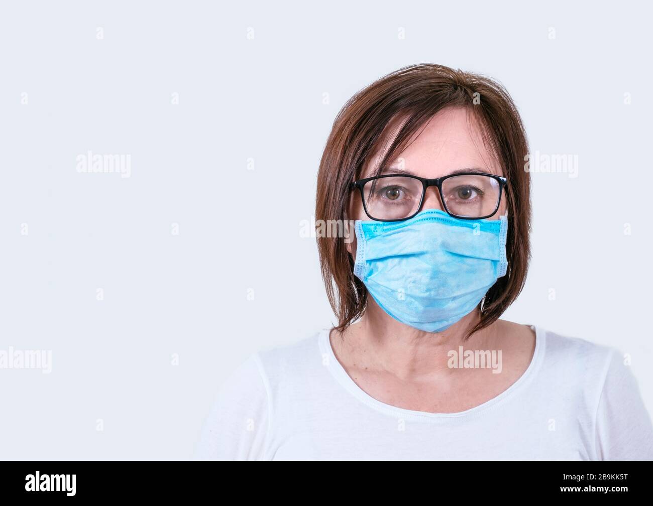 Portrait d'une femme d'âge moyen dans un masque médical. Femme malade âge moyen dans les verres sur le fond blanc. Banque D'Images