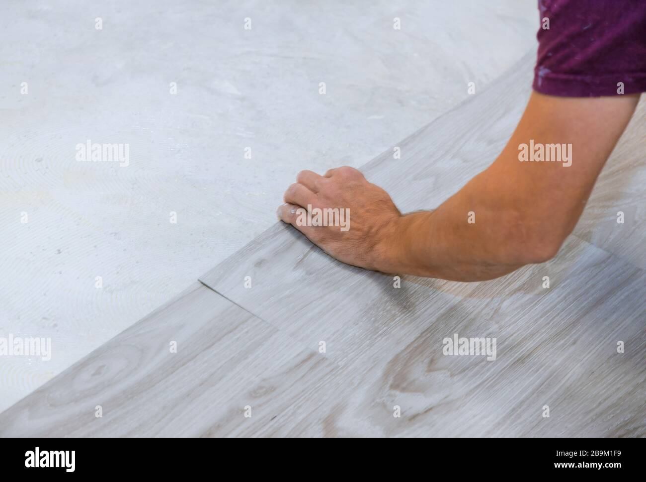 Travail sur le travail de pose installer nouveau plancher de texture de bois de carrelage en vinyle. Banque D'Images