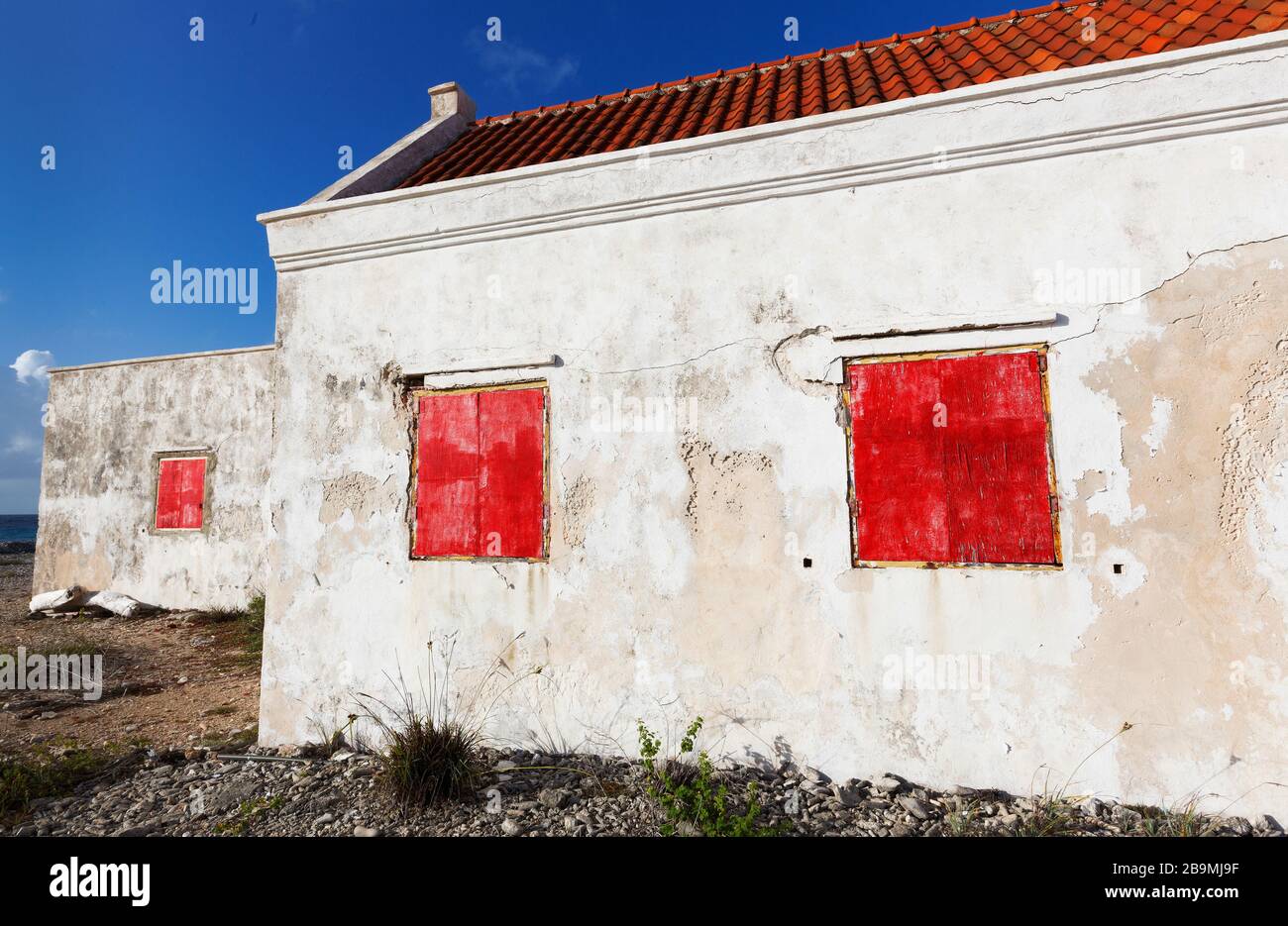 Ancienne maison blanche abandonnée avec volets de fenêtre rouge sur la côte de Bonaire partie des îles ABC, Pays-Bas Antillies, Caraïbes Banque D'Images