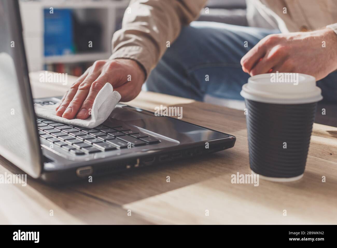 L'homme désinfecte son ordinateur portable, nettoyage du clavier . Essuyer avec de l'alcool nettoyant et du désinfectant Banque D'Images