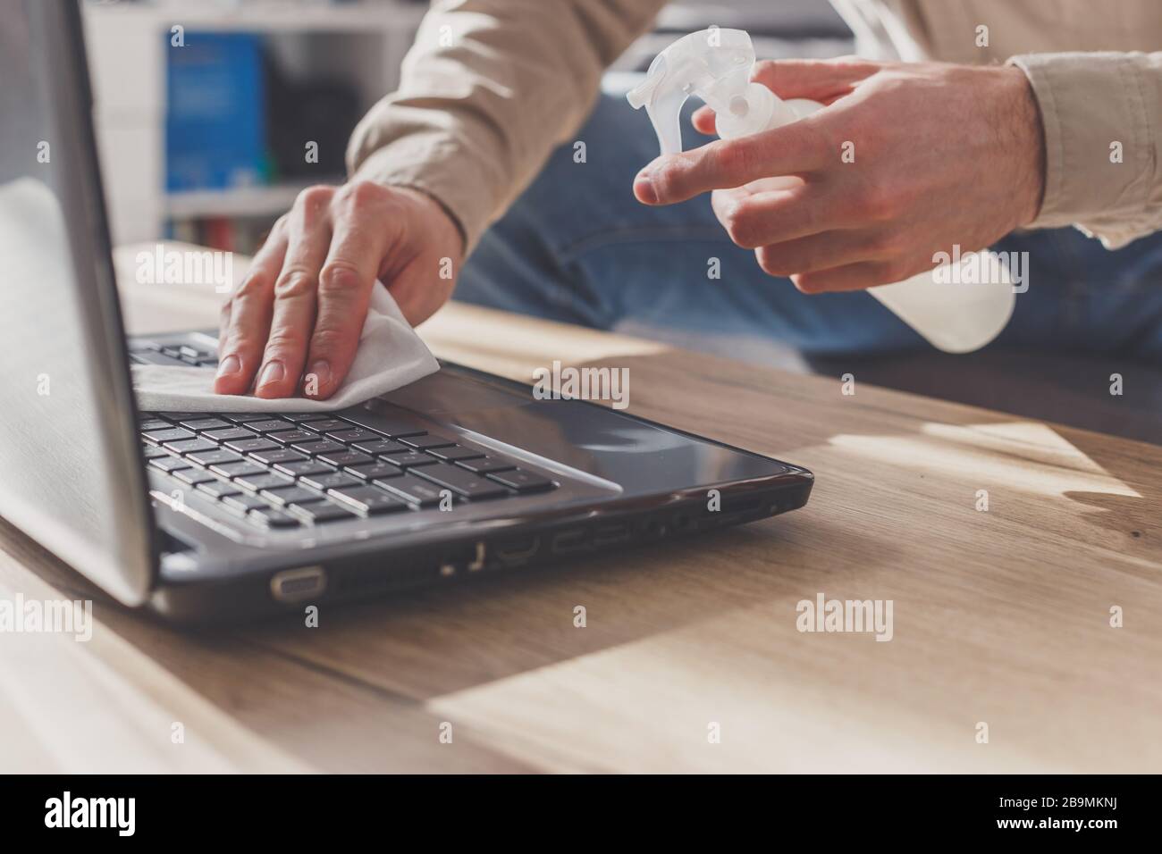 L'homme désinfecte son ordinateur portable, nettoyage du clavier . Essuyer avec de l'alcool nettoyant et du désinfectant Banque D'Images