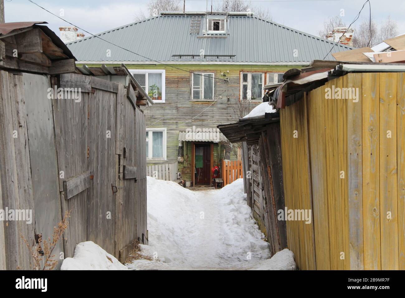 Maison en bois de deux étages entourée de hangars en bois en hiver russe. Illustration du stock pour le Web et l'impression avec un espace vide pour le texte et la conception. Banque D'Images