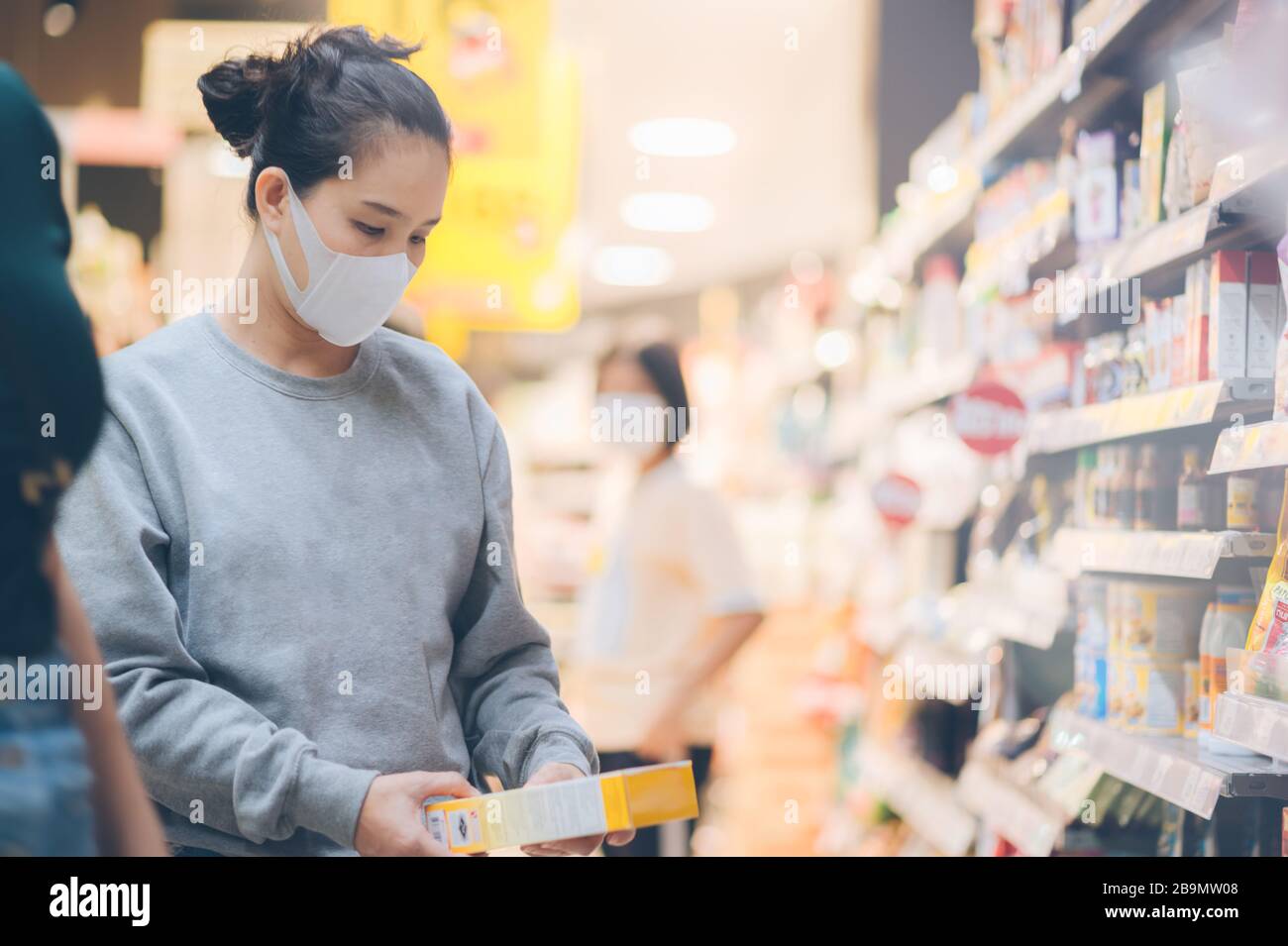 Femme asiatique portant un masque dans le supermarché, les achats de Panic pendant Coronavirus covid-19 pandémique.les achats de budget dans un magasin d'approvisionnement.Achat de smar congélateur Banque D'Images
