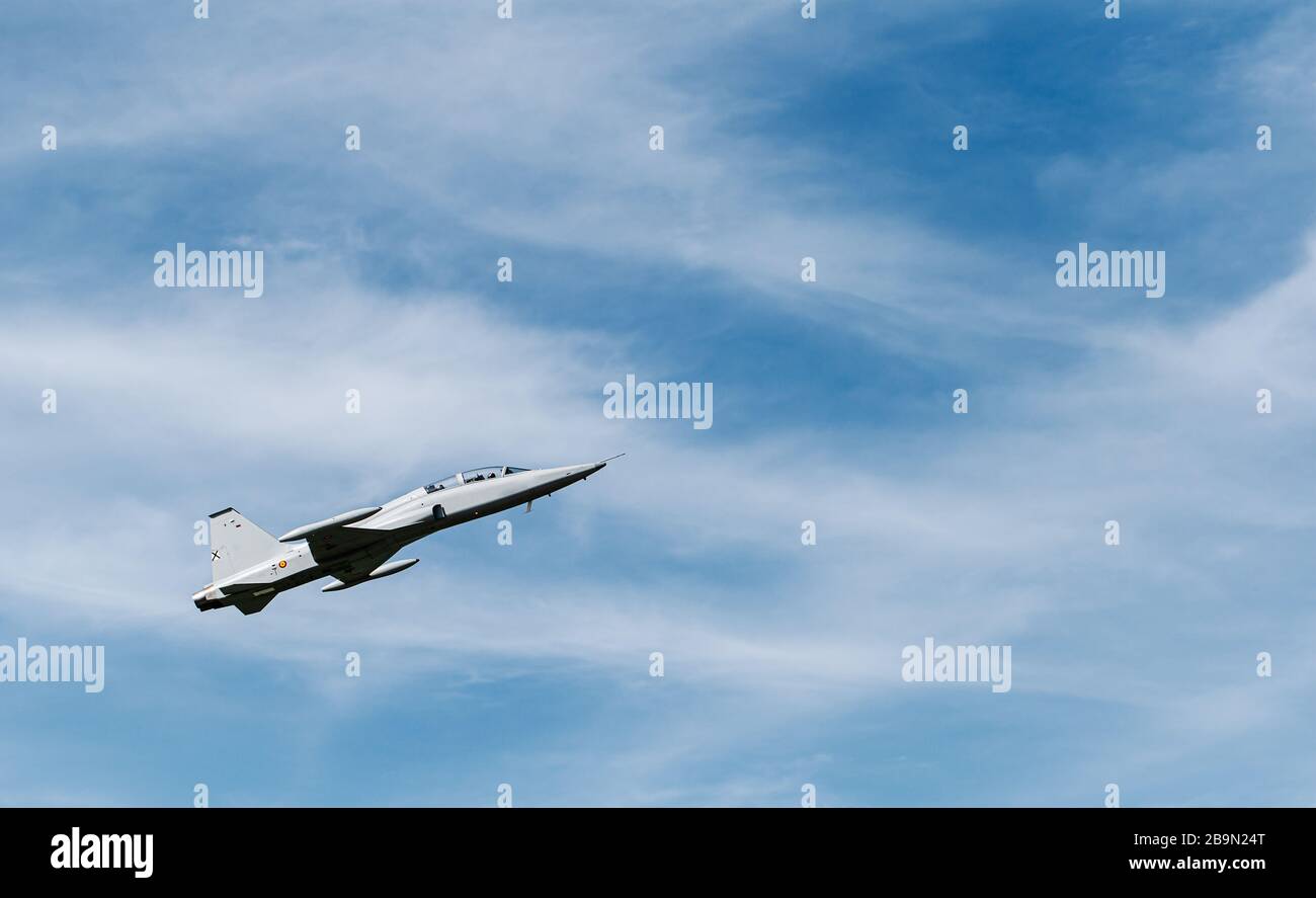 Un avion d'entraînement militaire qui se déroule avec le ciel bleu et les nuages en arrière-plan Banque D'Images
