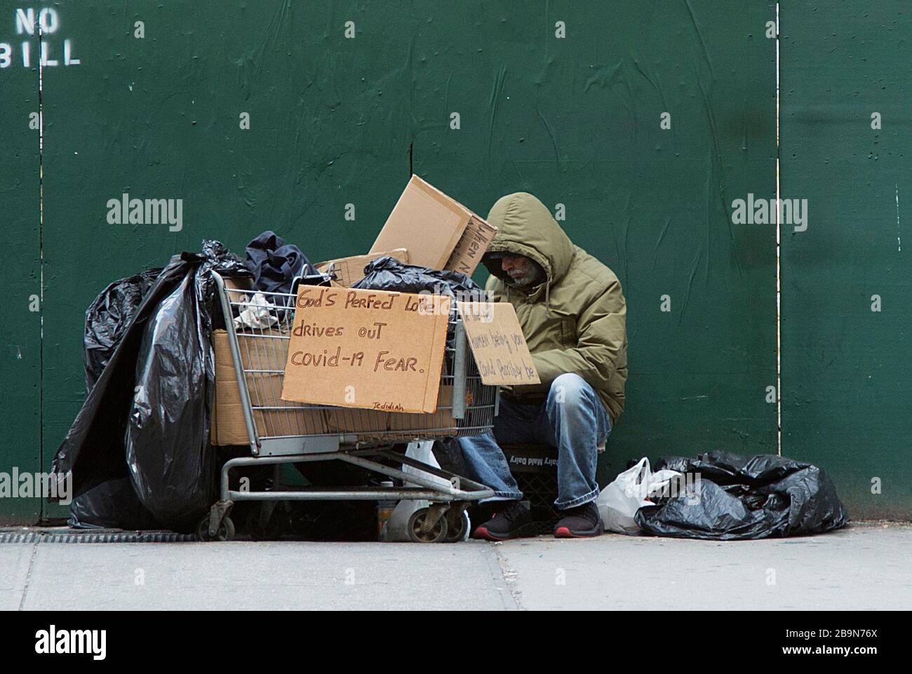 Un homme sans abri affiche un signe qui nous dit que seul l'amour de Dieu dissipera la peur causée par le coronavirus Covid-19. 5e Avenue, Midtown Manhattan, New York. Banque D'Images