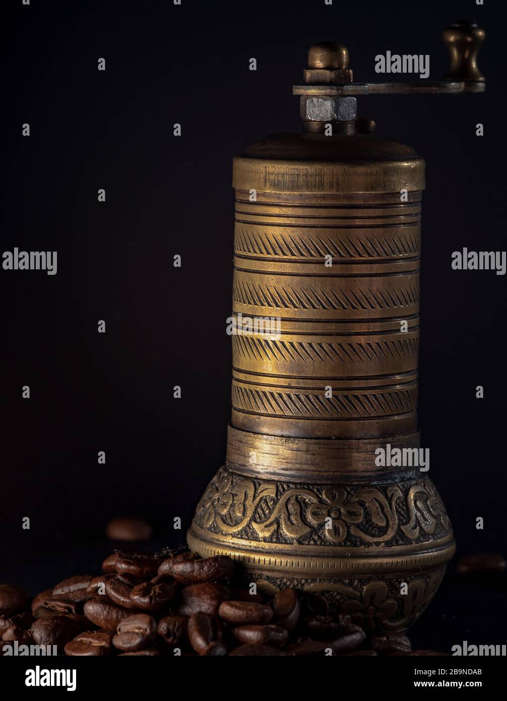 Moulin à café en laiton sur fond noir avec grains de café torréfiés. Isolé sur fond noir Banque D'Images