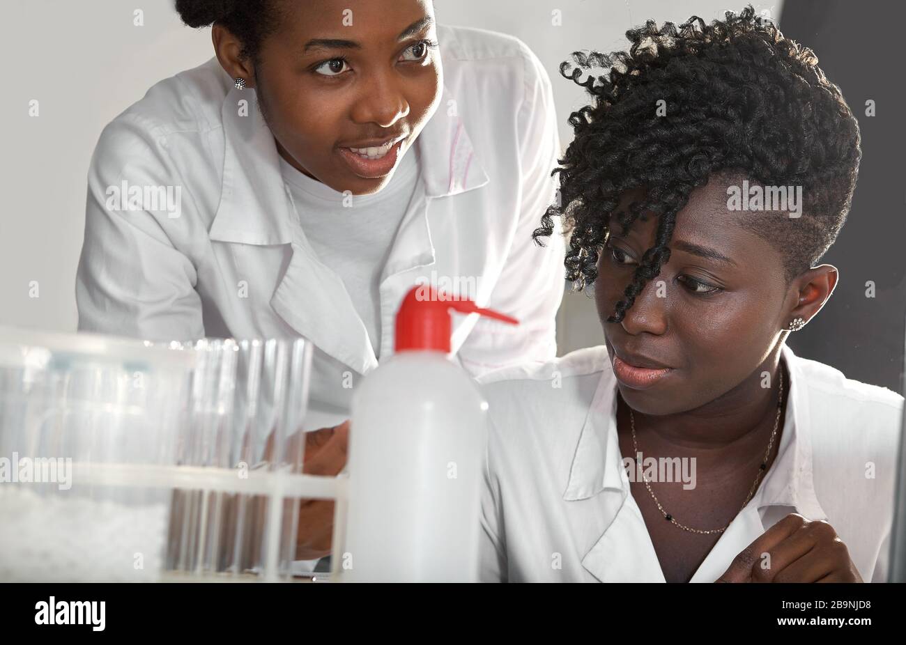 Фemale les étudiants africains en médecine, les jeunes diplômés en laboratoire de tests médicaux effectuent divers testicules sur des échantillons de patients. Analyse microscopique b Banque D'Images