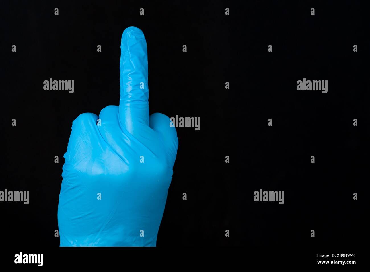 Une main gantée bleue avec le doigt central sorti. Le gant est en latex bleu. Fond noir. Banque D'Images