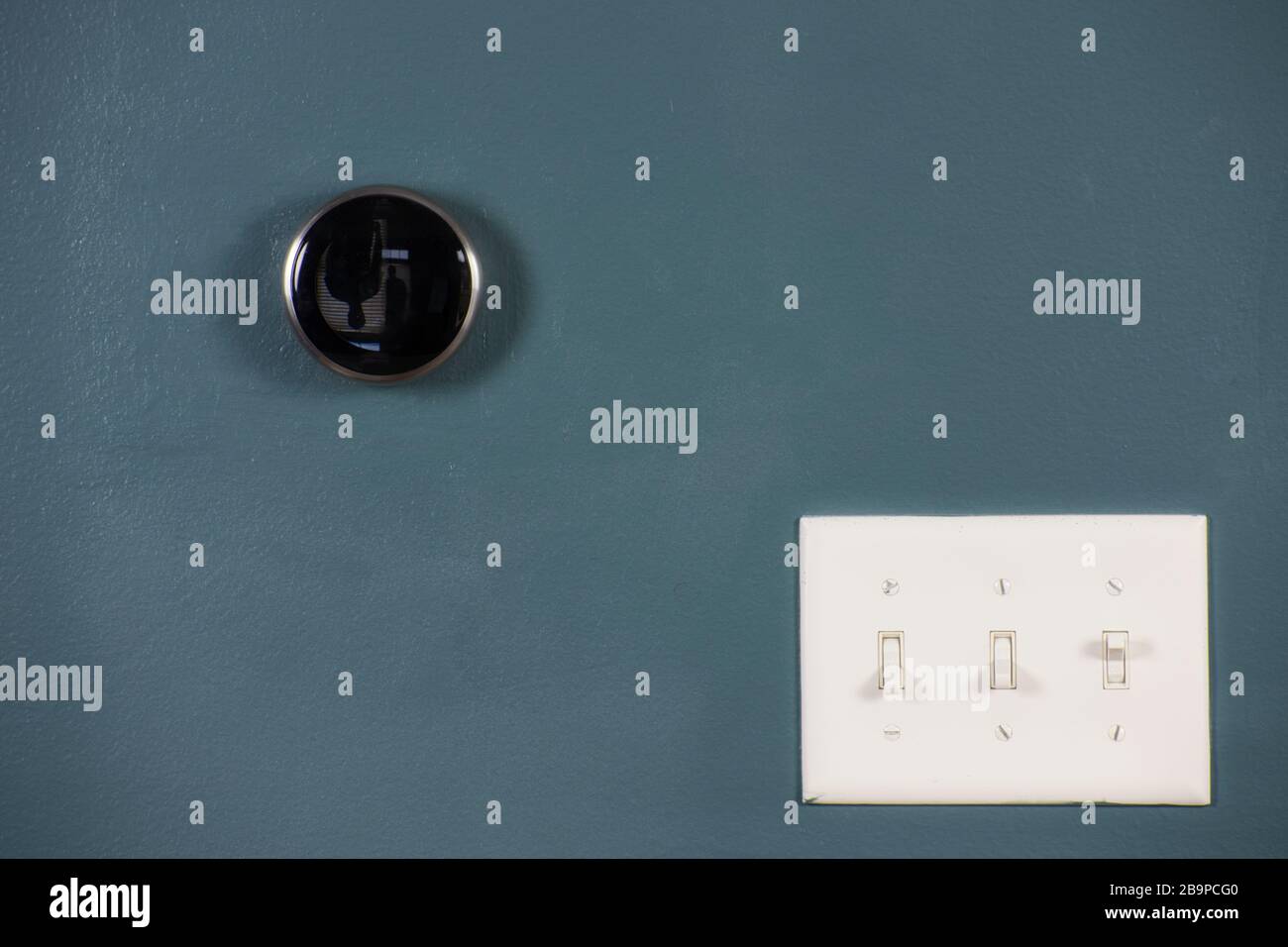 Thermostat d'ambiance intelligent isolé sur une paroi bleue avec interrupteur d'éclairage. Plusieurs façons d'économiser de l'argent et de l'énergie. Banque D'Images