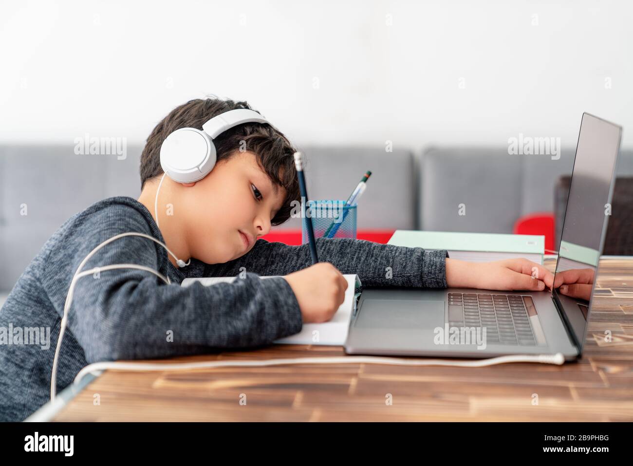 Un petit garçon étudie devant l'ordinateur portable. E apprentissage, étude à la maison en ligne Banque D'Images