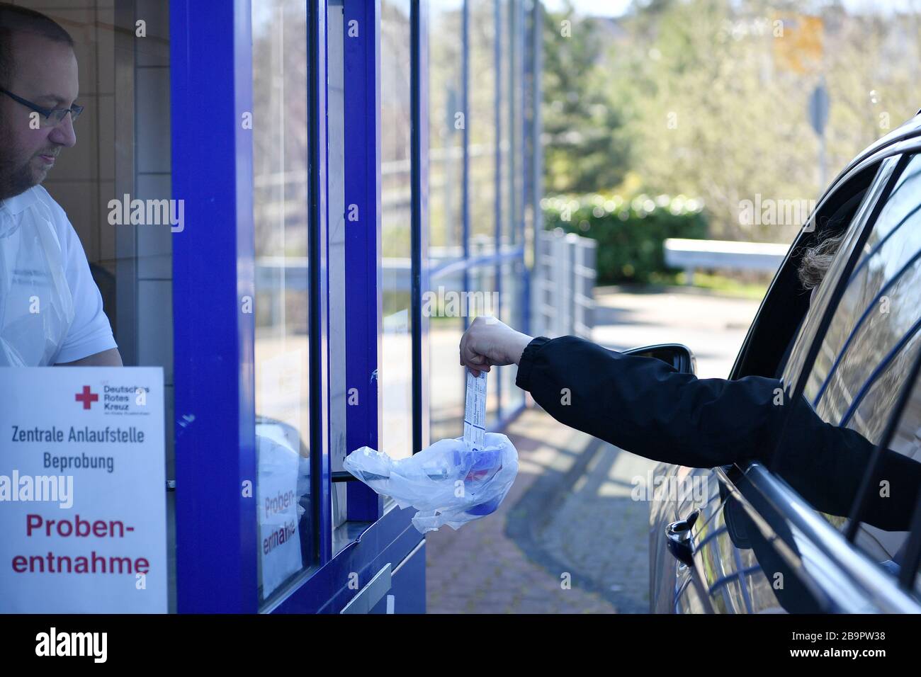 (200325) -- FRANCFORT, le 25 mars 2020 (Xinhua) -- un professionnel de la santé de la Croix-Rouge allemande prend un échantillon d'un conducteur pour tester une éventuelle infection au coronavirus dans une station d'essai en conduite à Mechernich, Allemagne, le 24 mars 2020. Les cas confirmés par l'Allemagne de COVID-19, la maladie causée par le nouveau coronavirus a augmenté de 4 764 en un jour à 27 436 mardi, a annoncé le Robert Koch Institute (RKI) mardi. Jusqu'à présent, l'Allemagne a enregistré 114 décès mardi, selon RKI, l'agence fédérale et l'institut de recherche responsable de la lutte contre la maladie et de la prévention. (X Banque D'Images