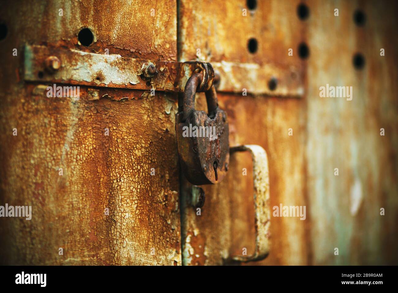 L'ancienne porte abandonnée rouillée est fermée sur une ancienne grande grange avec un petit trou de serrure. Banque D'Images