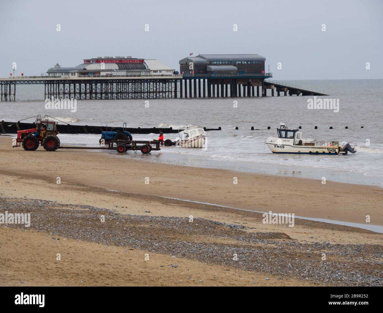 Pêcheurs utilisant des tracteurs pour tirer des bateaux sur la plage, Cromer, Norfolk, Royaume-Uni Banque D'Images