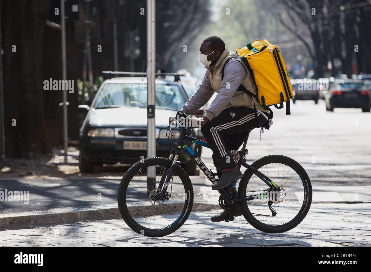 Homme de livraison de nourriture sur vélo travailler avec masque de protection pendant l'éclusage de Coronavirus en Italie Banque D'Images