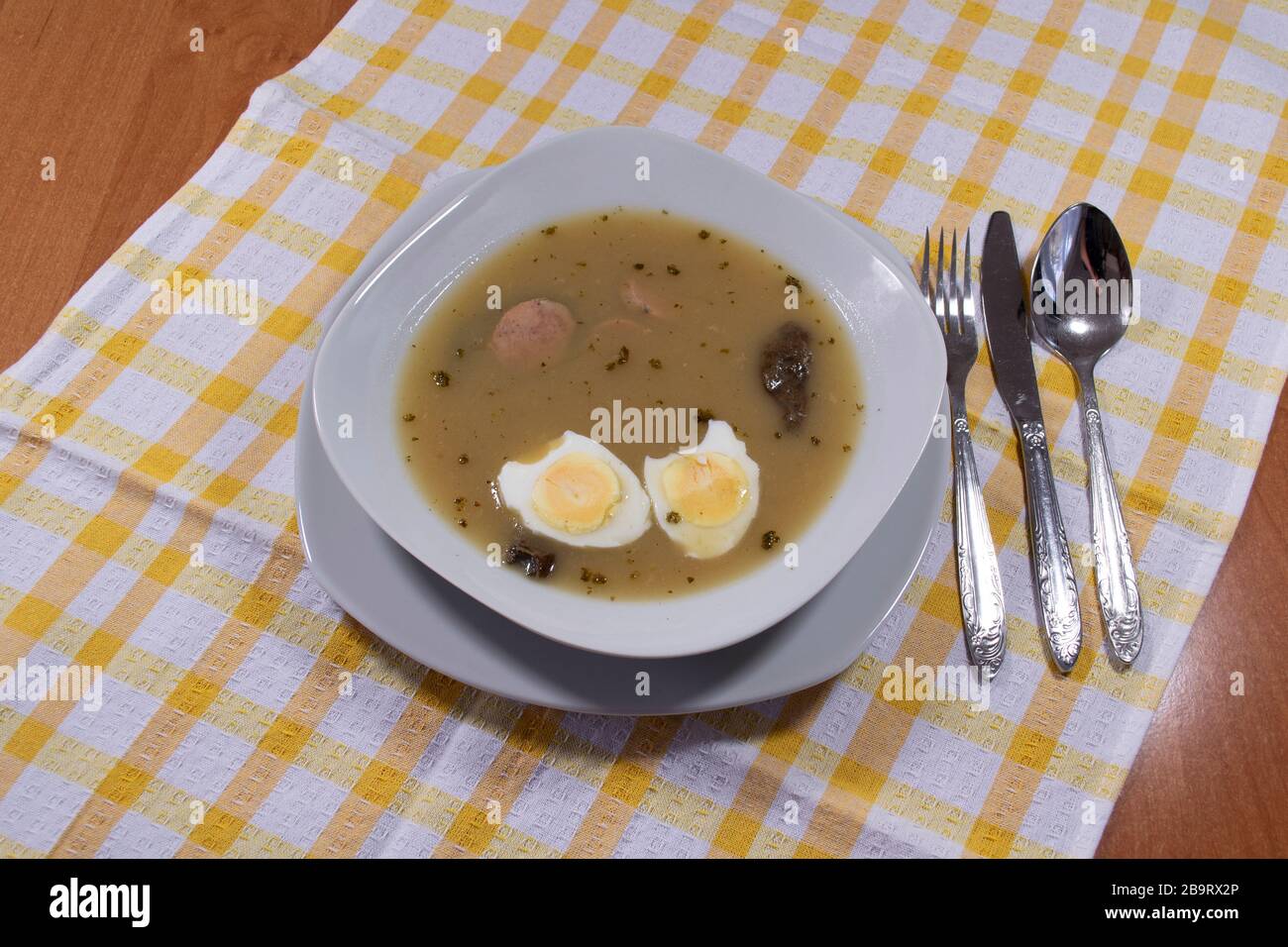 Cuisine traditionnelle polonaise - soupe aigre blanche avec œufs et saucisses blanches. Banque D'Images