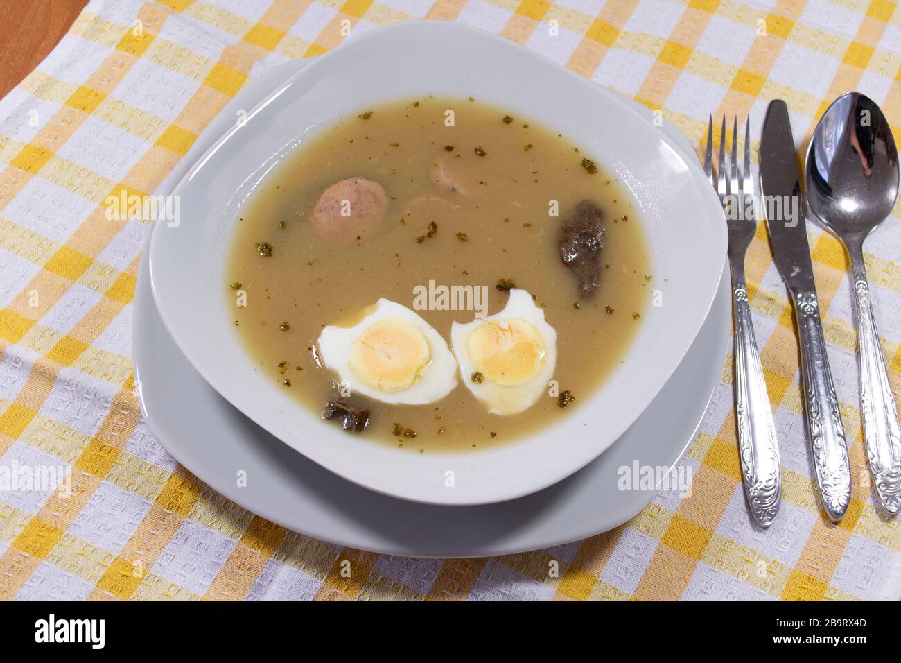 Cuisine traditionnelle polonaise - soupe aigre blanche avec œufs et saucisses blanches. Banque D'Images