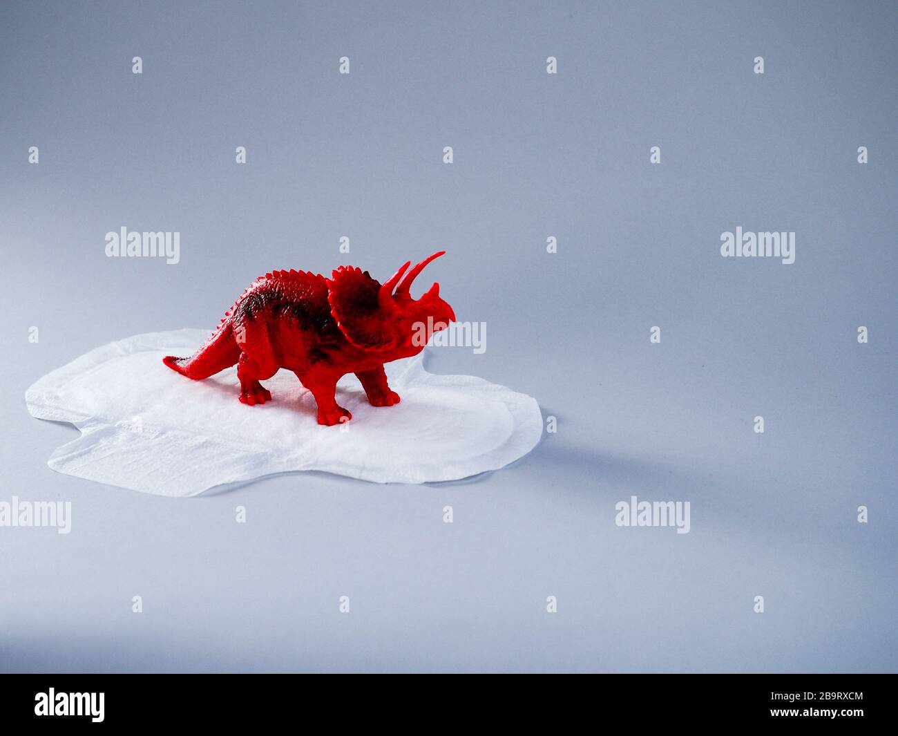 Tampon menstruel avec triceratops rouges sur fond gris. Concept minimaliste de photographie de la vie. Femmes jours critiques, menstruations gynécologiques cycl Banque D'Images