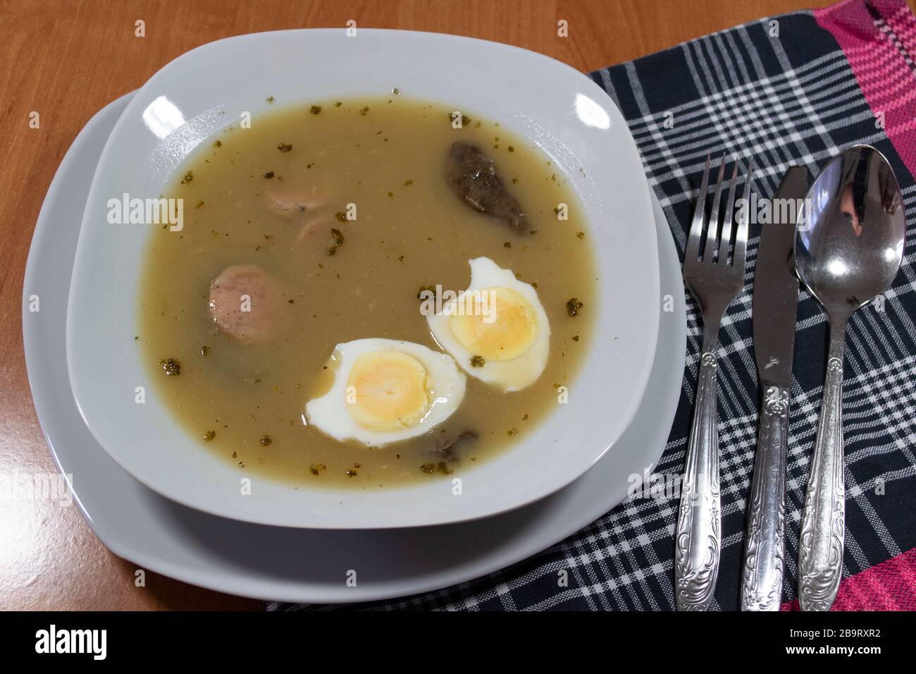 Cuisine traditionnelle polonaise - soupe aigre blanche avec œufs et saucisses blanches. Banque D'Images