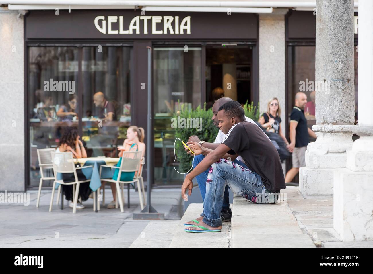 CRÈMES, ITALIE - 2 SEPTEMBRE 2015 : deux hommes noirs s'assoient sur les marches du bâtiment avec un téléphone dans les mains. Cremona. Italie Banque D'Images