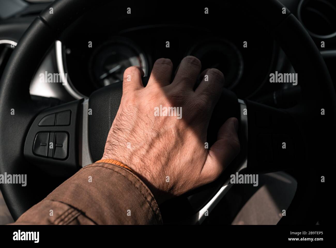 Actionner l'avertisseur sonore de la voiture en cas de bourrage de circulation, gros plan sur la main mâle du volant du véhicule avec mise au point sélective Banque D'Images