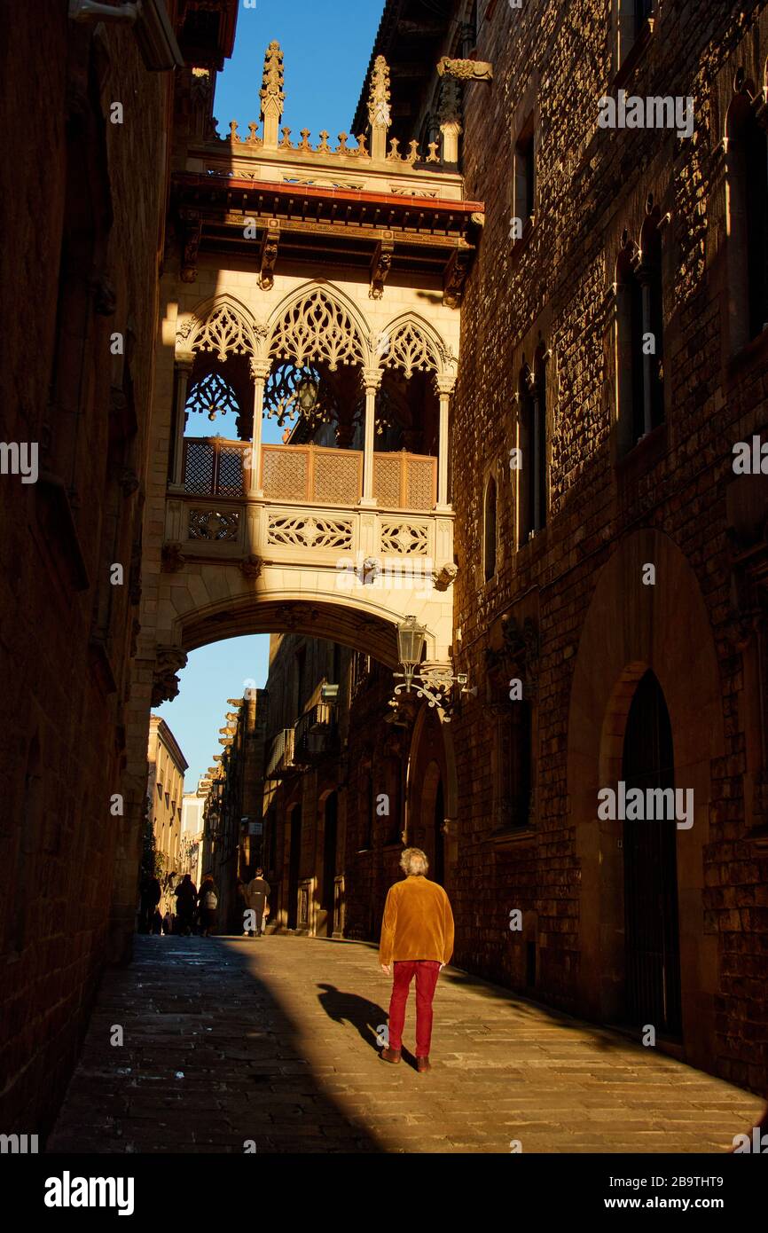 Les gens marchant sous le Pont del Bisbe au lever du soleil dans le Gotic de Bari à Barcelone, en Espagne Banque D'Images