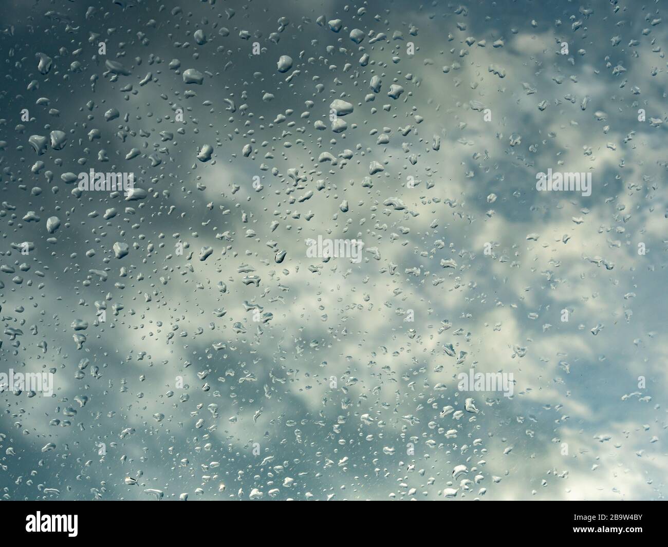 Fenêtre humide avec gouttes de pluie et ciel nuageux à l'extérieur de l'arrière-plan. Banque D'Images