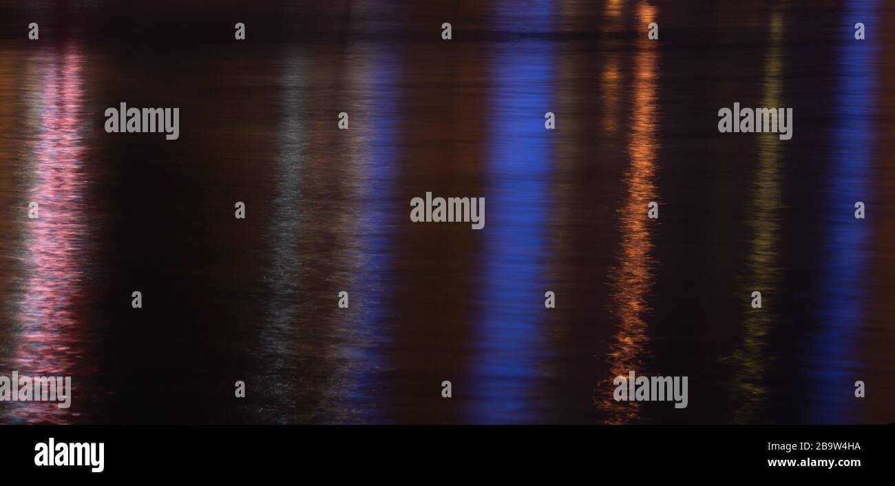 Réflexion lumineuse colorée sur la surface de l'eau. Vagues d'eau de mer la nuit. Texture de fond. Banque D'Images