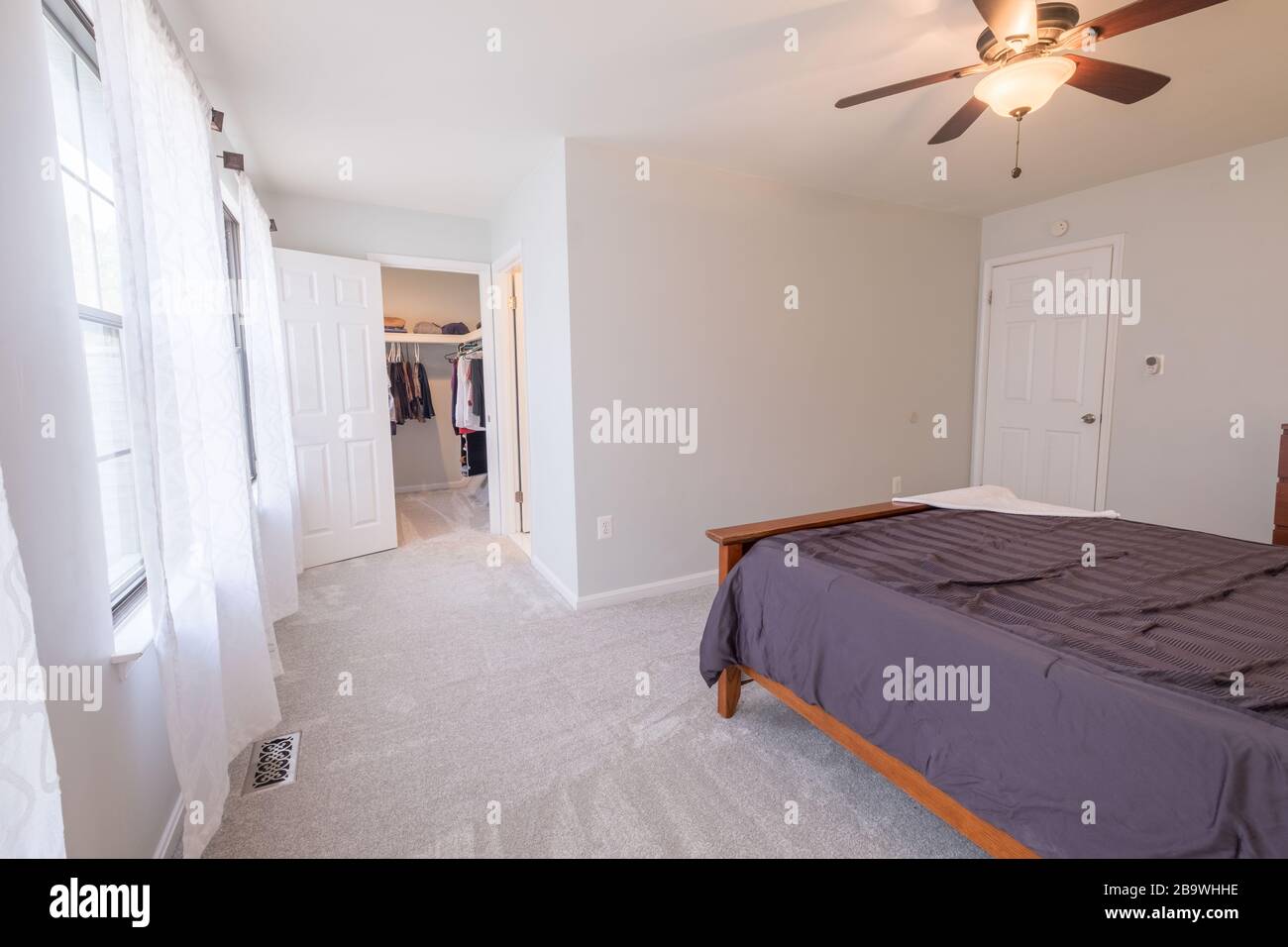 Belle photo d'une chambre avec un lit double, placard, et un ventilateur de plafond avec lumière Banque D'Images