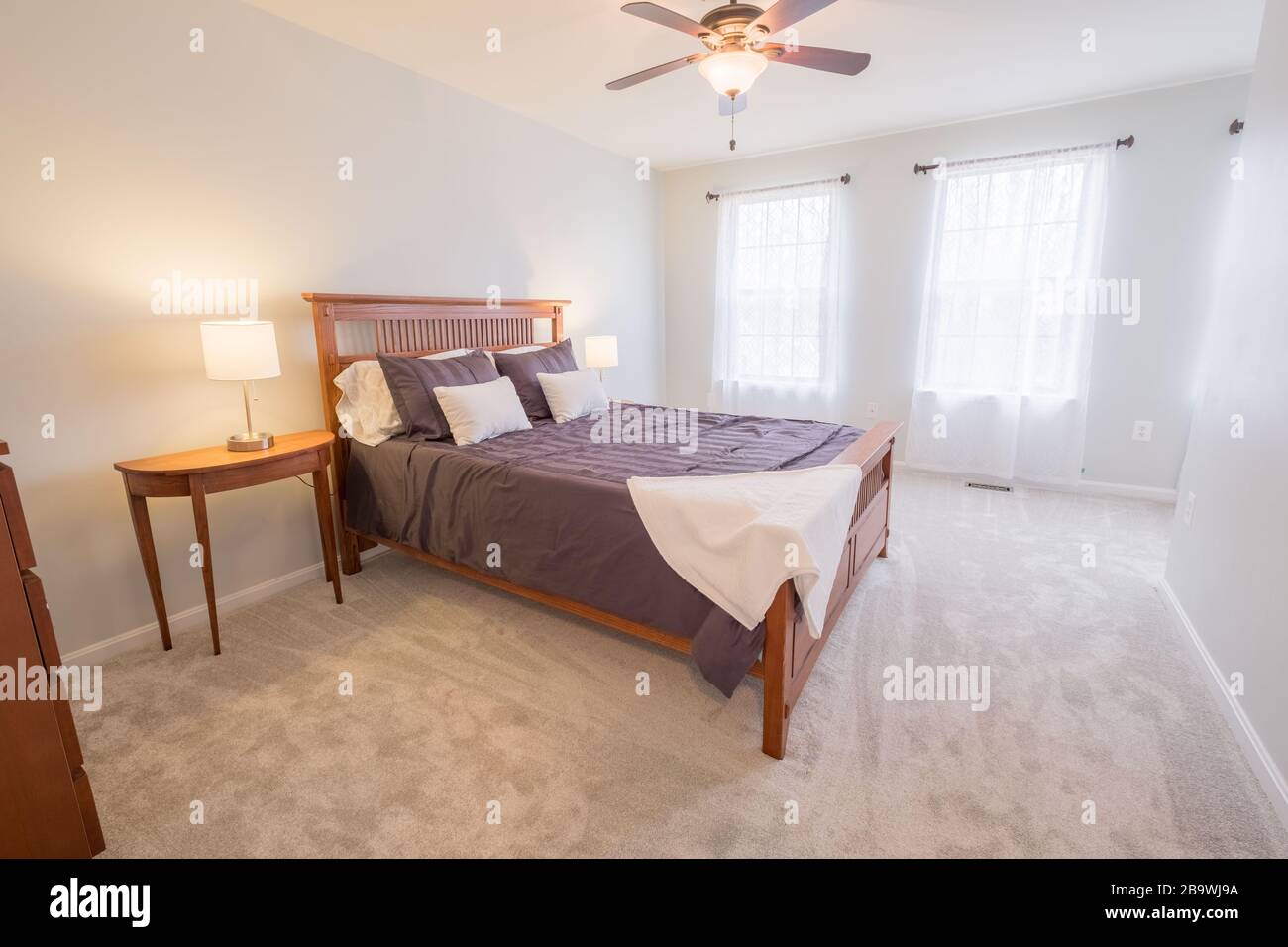 Belle photo d'une chambre avec un lit double, une lampe sur la table et un ventilateur de plafond Banque D'Images