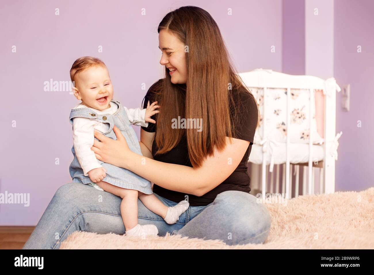 Maman joue avec sa fille de nouveau-né dans la chambre. Le concept de famille, de maternité et de garde d'enfants. Banque D'Images