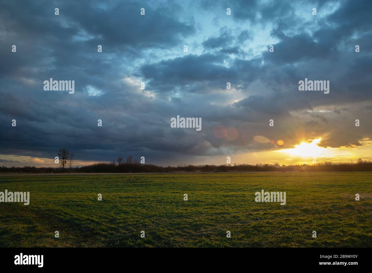 Ciel pluvieux et coucher de soleil sur la prairie verte Banque D'Images