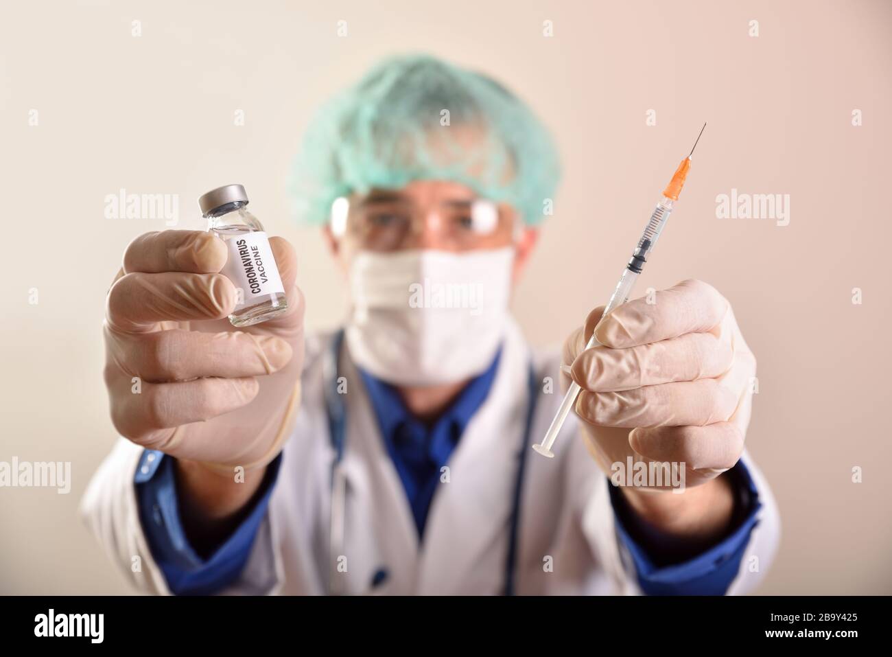 Médecin avec flacon de vaccin contre le virus covid-19 et seringue dans ses mains avec protection du visage et des mains sur fond brun isolé Banque D'Images