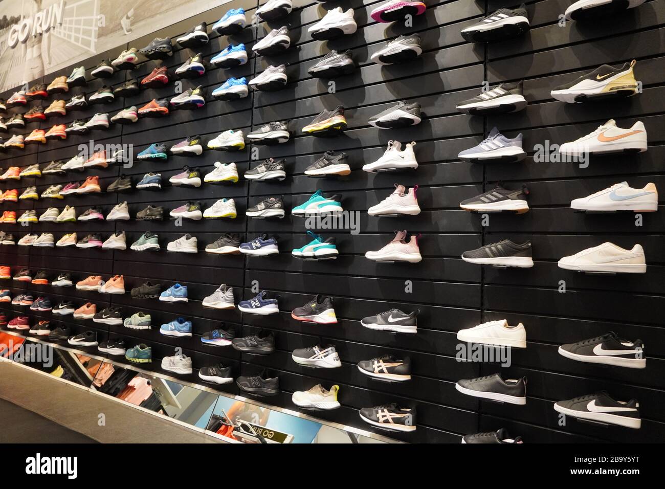 Voir l'affichage de beaucoup de chaussures de sport sur un mur. Vue sur un mur de chaussures à l'intérieur du magasin. Nouvelles chaussures de course à pied modernes et élégantes pour Homme et Homme Banque D'Images