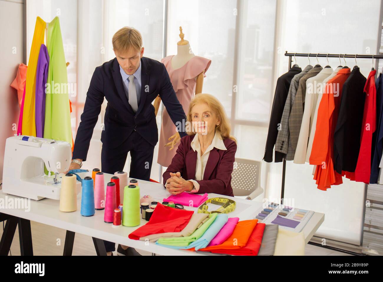 Des designers professionnels, de jeunes hommes et de femmes âgées dans la salle de travail avec différents tissus de couleurs Banque D'Images