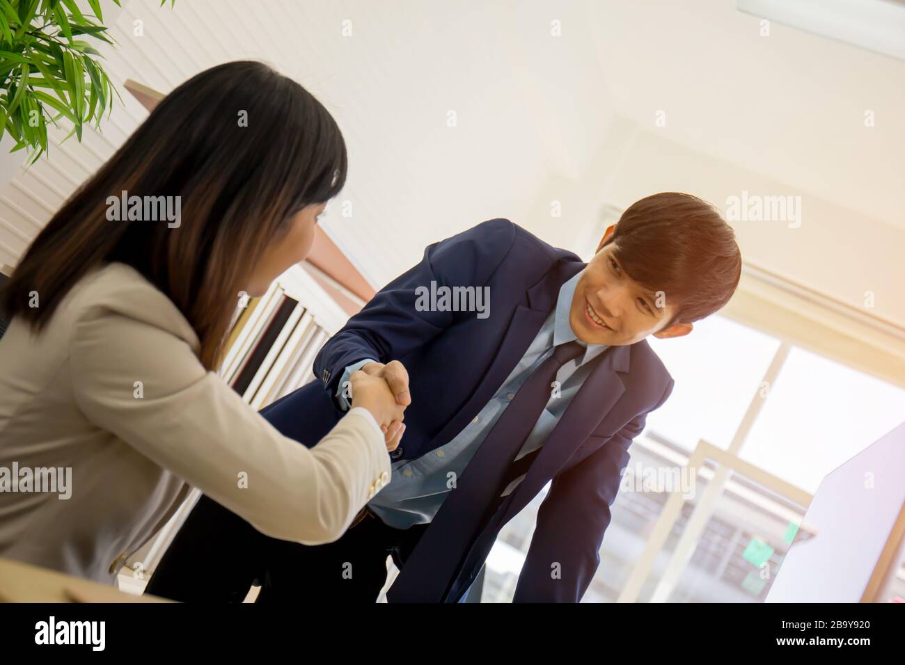 Deux hommes d'affaires et femmes d'affaires se serrent les mains dans le bureau de réunion avec un visage souriant Banque D'Images