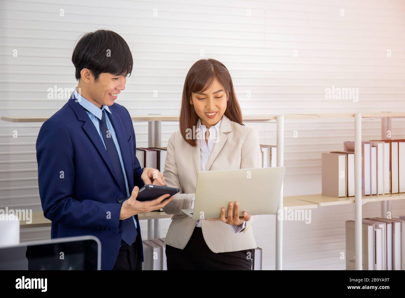Deux jeunes hommes d'affaires asiatiques se réunissent au bureau à la main de la tablette. Banque D'Images