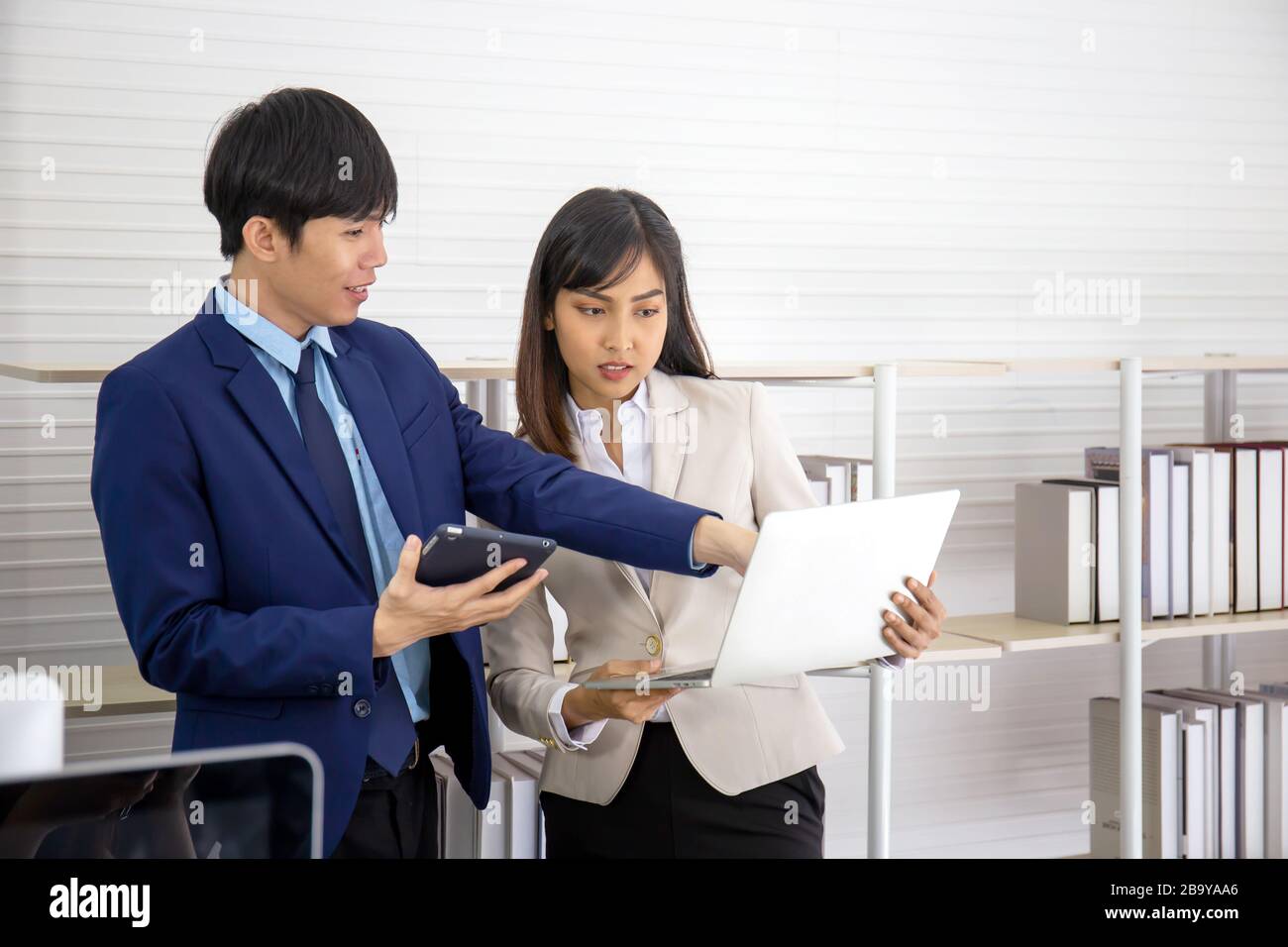 Deux jeunes hommes d'affaires asiatiques se réunissent au bureau à la main de la tablette. Banque D'Images