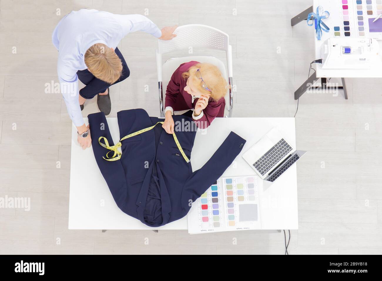 Topview les concepteurs professionnels de travail d'équipe, les jeunes hommes et les femmes âgées dans le bureau avec une variété de tons de tissu et d'équipement pour divers modèles. Banque D'Images