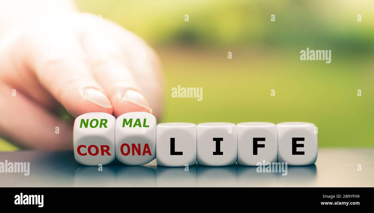 Retour à la normale. La main transforme les dés et change l'expression 'vie corona' en 'vie normale'. Banque D'Images