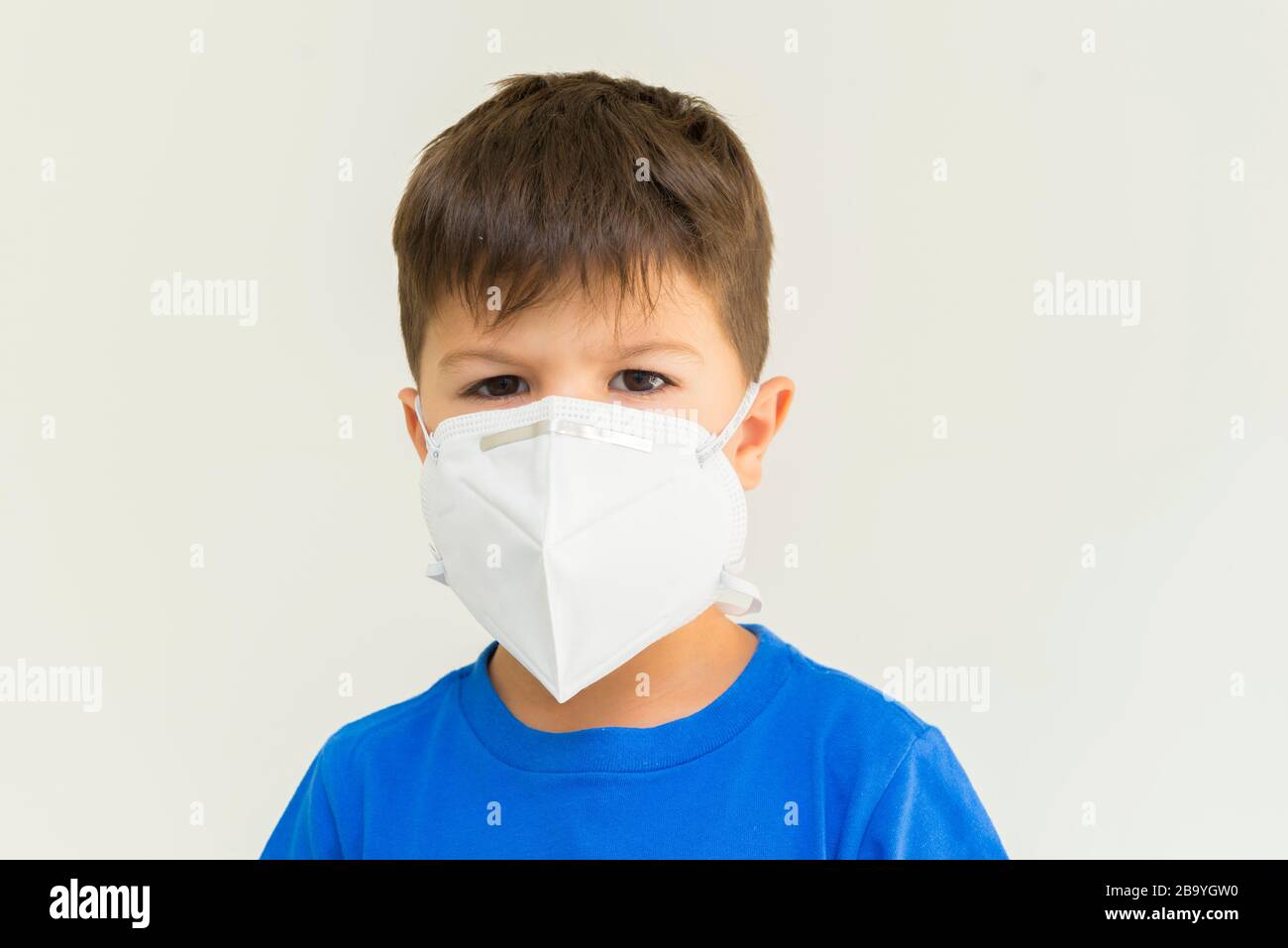Gros plan d'un garçon caucasien portant un masque chirurgical. Masque facial pour la protection contre les épidémies de coronavirus. Concept de protection contre la thrée biologique Banque D'Images