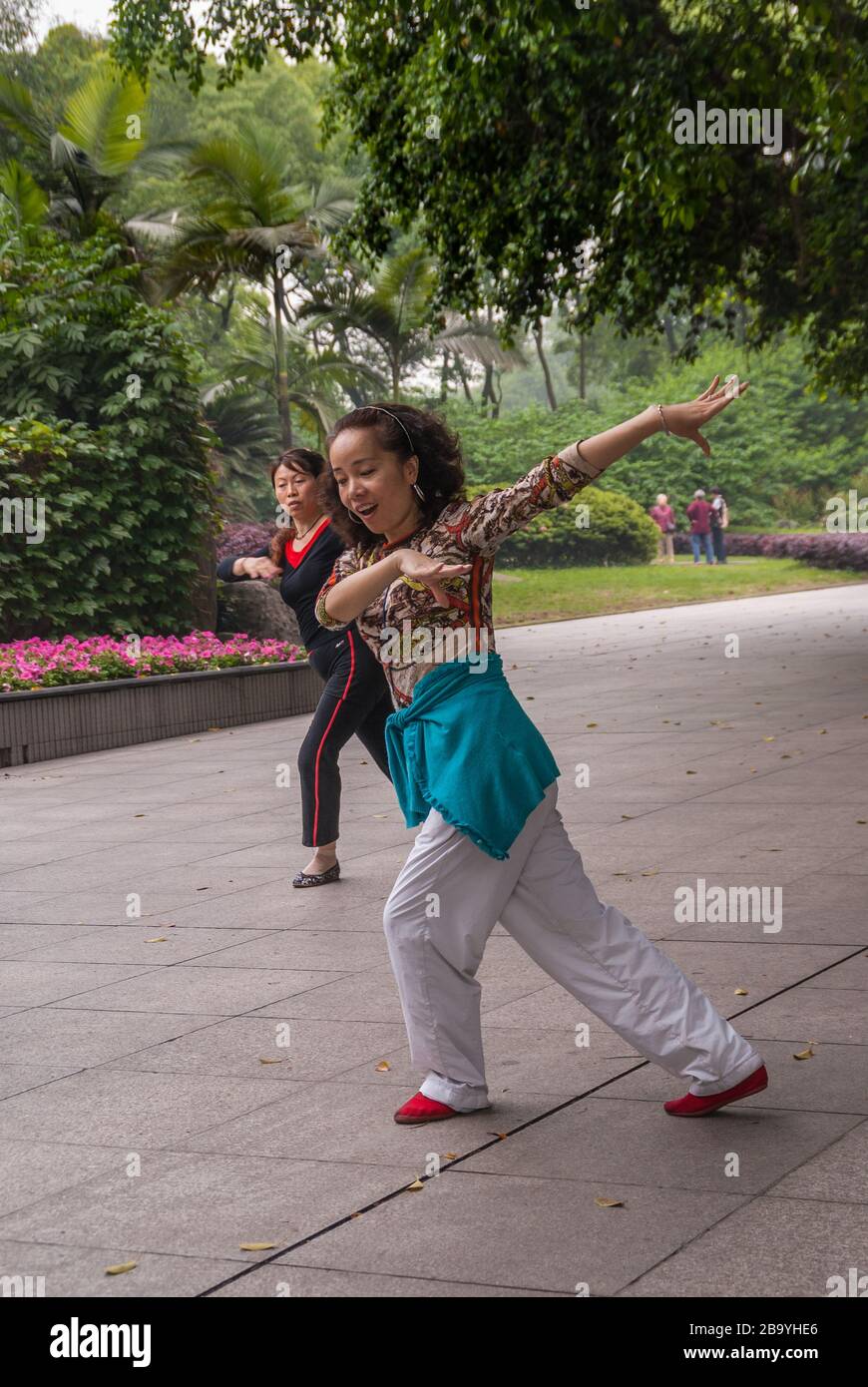 Chongqing, Chine - 9 mai 2010 : spectacle de danse de groupe dans le zoo Park. Gros plan de 2 femmes en mouvement synchronisé sur la musique. Feuillage vert. Banque D'Images
