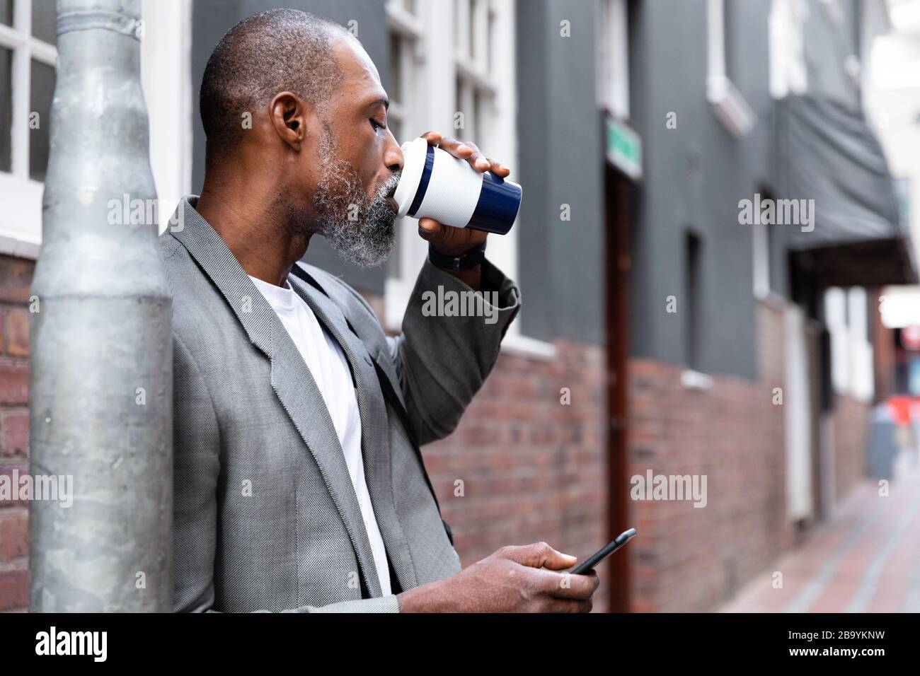 Homme africain américain utilisant son téléphone dans la rue Banque D'Images